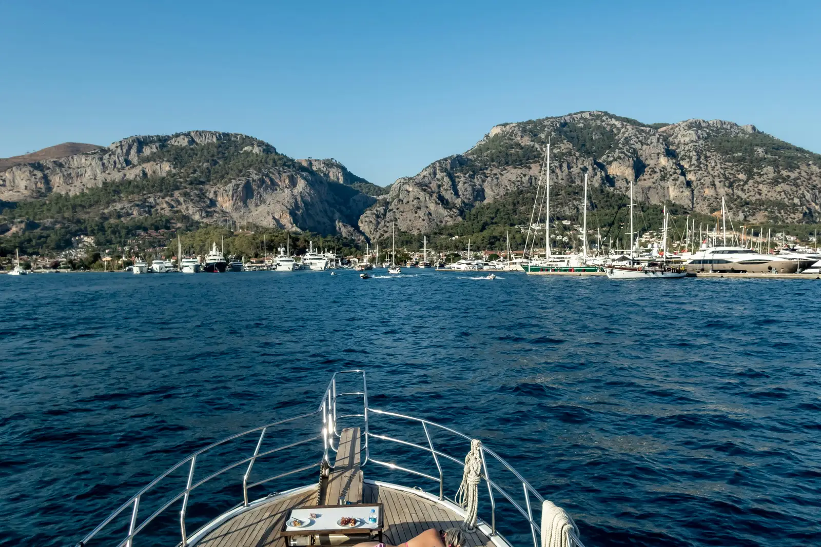 Pruvadan görünen marina, kayalık dağlar ve koyu mavi deniz
